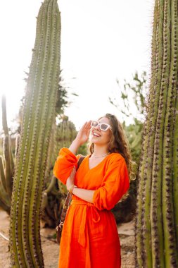 Kaktüslere karşı poz veren şık bir kadın turist. Açık hava yaz portresi. Pozitif duygular.