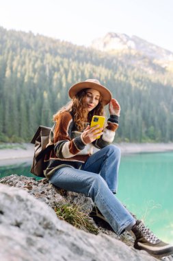 Genç bayan turist doğada akıllı telefon kullanıyor. Yürüyüş, spor, seyahat ve teknoloji konsepti.