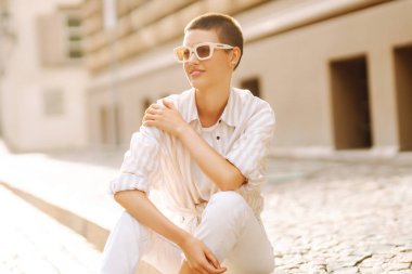 Kısa saçlı, mutlu kadın merdivenlerde oturuyor. Yaşam tarzı, moda, seyahat kavramı