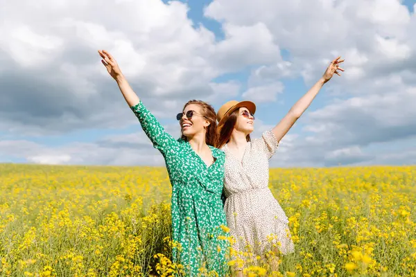 Çiçek açan alandaki iki çekici kadın. Doğa, tatil, rahatlama ve yaşam tarzı. Yaz manzarası.
