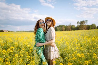 Çiçek açan alandaki iki çekici kadın. Doğa, tatil, rahatlama ve yaşam tarzı. Yaz manzarası.