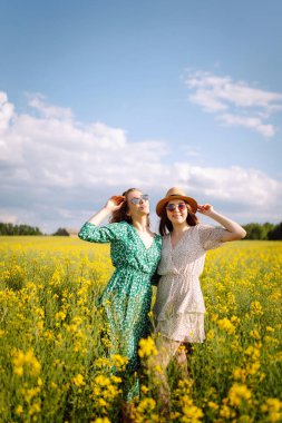 Çiçek açan alandaki iki çekici kadın. Doğa, tatil, rahatlama ve yaşam tarzı. Yaz manzarası.
