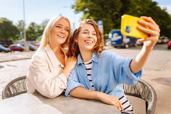 Kafede oturan mutlu güzel kızlar kamerayla selfie çeker. Moda, güzellik, blog, turizm.