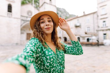 Seyahat ederken selfie. Genç bir kadın, eski şehrin arka planında akıllı bir telefondan selfie çekiyor. Yaşam tarzı, seyahat, turizm, hafta sonu.