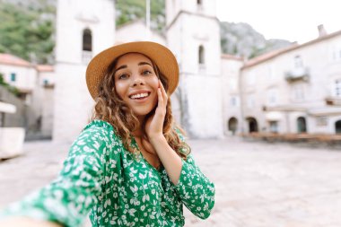 Seyahat ederken selfie. Genç bir kadın, eski şehrin arka planında akıllı bir telefondan selfie çekiyor. Yaşam tarzı, seyahat, turizm, hafta sonu.