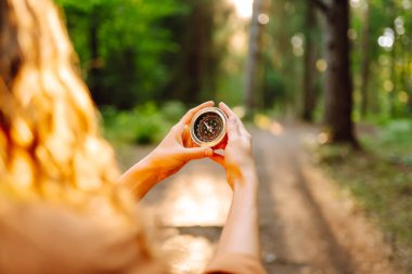 Seyrüsefer pusulasını tutan kadının elleri. Dişi gezgin pusulayı elinde tutuyor ve doğada yol gösteriyor. Yürüyüş konsepti, doğa..