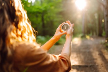 Seyrüsefer pusulasını tutan kadının elleri. Dişi gezgin pusulayı elinde tutuyor ve doğada yol gösteriyor. Yürüyüş konsepti, doğa..