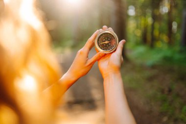 Seyrüsefer pusulasını tutan kadının elleri. Dişi gezgin pusulayı elinde tutuyor ve doğada yol gösteriyor. Yürüyüş konsepti, doğa..