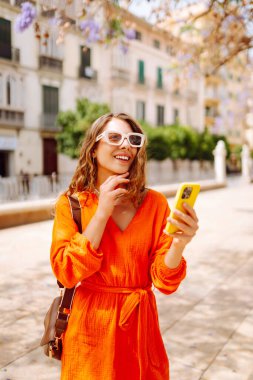 Cep telefonu kullanıp sokak pazarında rahatlayan genç ve mutlu bir bayan. Seyahat, turizm, teknoloji, blog, iletişim kavramı.