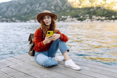 Şehir duvarında telefonla yürüyen güzel bir kadın. Tatillerde turist. Yaşam tarzı, seyahat, doğa, aktif yaşam.