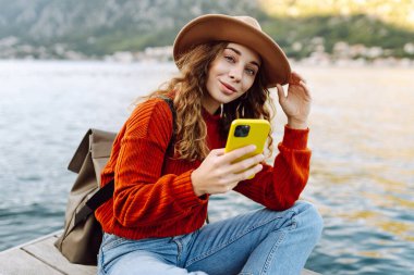 Şehir duvarında telefonla yürüyen güzel bir kadın. Tatillerde turist. Yaşam tarzı, seyahat, doğa, aktif yaşam.