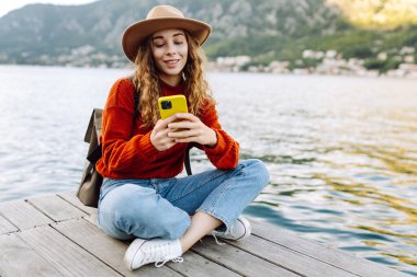 Şehir duvarında telefonla yürüyen güzel bir kadın. Tatillerde turist. Yaşam tarzı, seyahat, doğa, aktif yaşam.