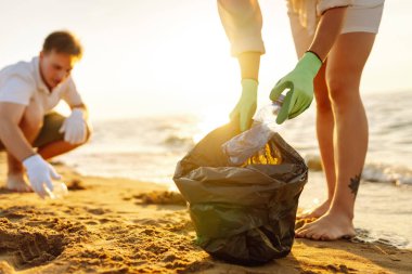 Okyanus kıyısındaki çöpleri temizliyorum. Polyethielene çantalı gönüllüler plajdan plastik bir şişe alıyor. Ekolojinin korunması kavramı. Dünya günü.