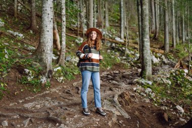 Aktif bir kadın ormanda yürüyüşe çıkar ve patika boyunca yürür. Dişi yürüyüşçü ormanı keşfediyor. Doğa, seyahat, dinlenme konsepti.