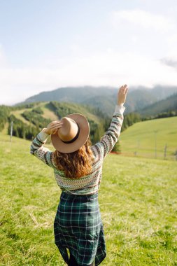 Yeşil çimen tarlasında yürüyen mutlu kadın manzaraya hayran. Macera ve seyahat keşfi