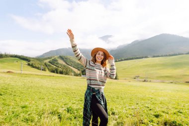 Yeşil çimen tarlasında yürüyen mutlu kadın manzaraya hayran. Macera ve seyahat keşfi