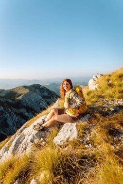 Kadın Gezgin, sırt çantasıyla dağlarda durup manzaraya hayran. Seyahat yaşam tarzı. Açık havada yaz tatili kavramları.