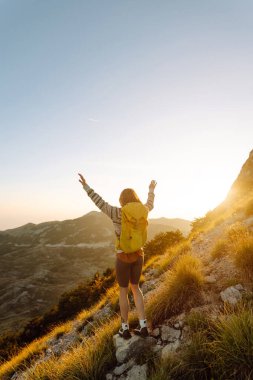 Kadın Gezgin, sırt çantasıyla dağlarda durup manzaraya hayran. Seyahat yaşam tarzı. Açık havada yaz tatili kavramları.
