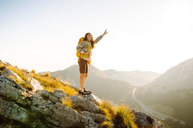 Kadın Gezgin, sırt çantasıyla dağlarda durup manzaraya hayran. Seyahat yaşam tarzı. Açık havada yaz tatili kavramları.