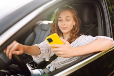 Kadın sürücü arabada akıllı telefon kullanıyor. Boş zaman, seyahat, teknoloji, navigasyon.