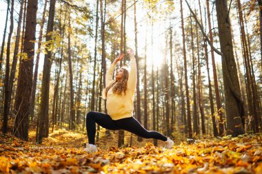 Huzurlu doğal ormanda yoga yapan genç bir kadın. Yaşam tarzı ve meditasyon konsepti.