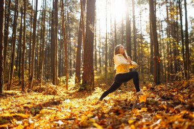 Huzurlu doğal ormanda yoga yapan genç bir kadın. Yaşam tarzı ve meditasyon konsepti.