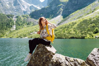 Genç bayan gezgin, tepenin üstünde dururken güzel doğasını gösteriyor. Seyahat, macera. Etkin bir yaşam biçimi kavramı.