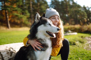 Genç bir kadın, parktaki çimenlikte köpeğiyle yürüyor. Birlikte oynuyoruz. Arkadaşlık kavramı, evcil hayvan, tatil.