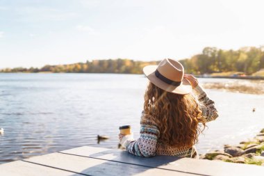 Genç bir kadın gölün arka planında kahve içerek rahatlıyor. Seyahat, kamp, doğa konsepti.