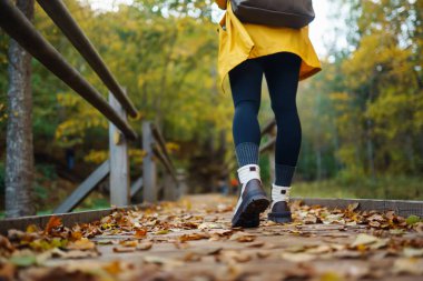 Açık havada yürüyüş ayakkabılarıyla yürümek. Güneşli bir sonbahar parkında yaprakların arasında dağlık bir alanda yürüyüş botlarıyla ayakların yakın çekimi..