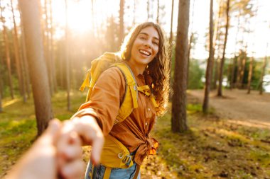Konseptimi takip edin ve birlikte seyahat edin. Mutlu kadın erkek arkadaşının elini tutuyor ve ormanda yürüyor. Tatil, turizm. Yürüyüş.