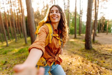 Konseptimi takip edin ve birlikte seyahat edin. Mutlu kadın erkek arkadaşının elini tutuyor ve ormanda yürüyor. Tatil, turizm. Yürüyüş.