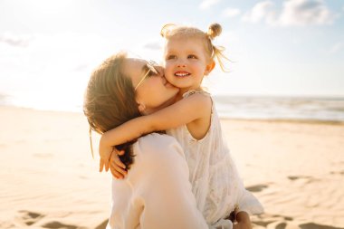Anne gün batımında tatil sırasında kızıyla sahilde yürür. Seyahat, turizm, hafta sonu konsepti. Aile partisi.