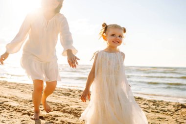 Anne gün batımında tatil sırasında kızıyla sahilde yürür. Seyahat, turizm, hafta sonu konsepti. Aile partisi.