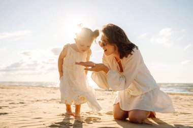 Anne gün batımında tatil sırasında kızıyla sahilde yürür. Seyahat, turizm, hafta sonu konsepti. Aile partisi.
