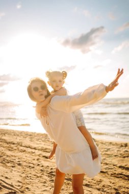 Anne gün batımında tatil sırasında kızıyla sahilde yürür. Seyahat, turizm, hafta sonu konsepti. Aile partisi.