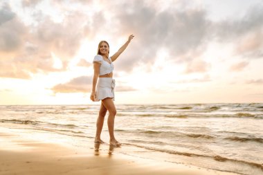 Muhteşem gün batımına bakan mutlu bir turist. Gün batımında deniz manzarası ve güzel bir gökyüzü. Seyahat, hafta sonu, rahatlama ve yaşam tarzı konsepti.