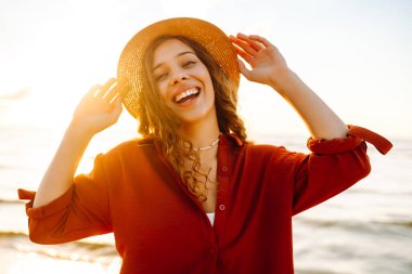 Kaygısız kadın turist gün batımında okyanus kumsalında yürüyor. Seyahat, hafta sonu, rahatlama ve yaşam tarzı konsepti.