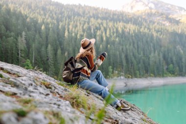 Sırt çantalı aktif bir kadın vahşi doğanın tadını çıkarıyor. Dağlar, göl, yeşil ormanlar. Pozitif duygular inanılmaz manzara.