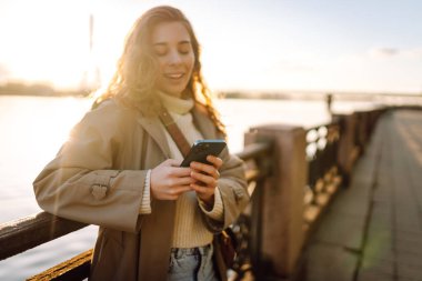 Sadece setin üzerinde duran cep telefonu olan genç bir kadın. İnternetten alışveriş yapan, sosyal medyayı izleyen ya da açık havada mobil uygulamalarla sohbet eden kadınlar..