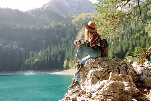 Sırt çantalı aktif bir kadın vahşi doğanın tadını çıkarıyor. Dağlar, göl, yeşil ormanlar. Pozitif duygular inanılmaz manzara.