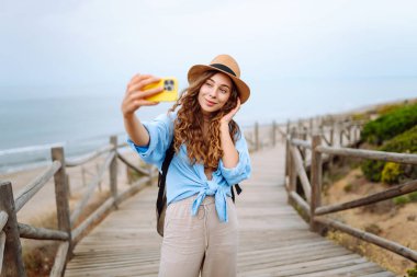 Kadın seyahat blogcusu doğa manzarasına hayran ve telefonda video blogu çekiyor. Yazın güneşli bir günde tek başına seyahat ederken cep telefonu kullanan Kafkas kadın gezgin..