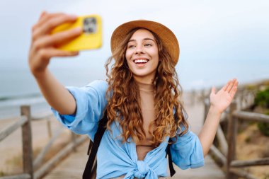 Kadın seyahat blogcusu doğa manzarasına hayran ve telefonda video blogu çekiyor. Yazın güneşli bir günde tek başına seyahat ederken cep telefonu kullanan Kafkas kadın gezgin..