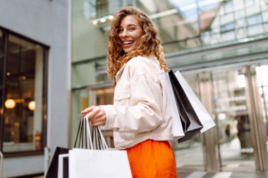 Şehirde alışveriş torbaları olan çekici genç bir kadın. Tüketim, alım, kara Cuma, yaşam tarzı, satış konsepti..
