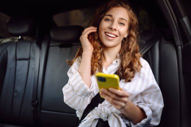 Emniyet kemeri takmış bir kadın içerideki telefonu kullanıyor. Teknoloji kavramı, araba ve iş seyahati..