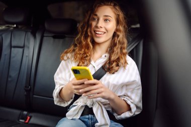 Emniyet kemeri takmış bir kadın içerideki telefonu kullanıyor. Teknoloji kavramı, araba ve iş seyahati..