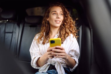 Emniyet kemeri takmış bir kadın içerideki telefonu kullanıyor. Teknoloji kavramı, araba ve iş seyahati..