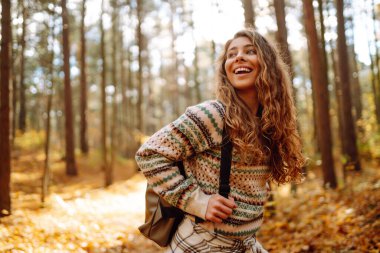 Sonbahar günü sırt çantasıyla ormanda yürüyüş yapan bir kadın yürüyüşçü. Doğa, seyahat, dinlenme konsepti.