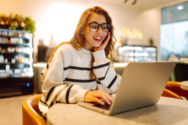 Serbest çalışan kadın, dizüstü bilgisayarda proje için iş arama konusuna odaklanmış, boş zamanlarında internet kurslarının internet sayfalarını karıştıran genç bir kadın ders çalışmaya başlamış. İnternetten alışveriş.