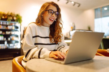 Serbest çalışan kadın, dizüstü bilgisayarda proje için iş arama konusuna odaklanmış, boş zamanlarında internet kurslarının internet sayfalarını karıştıran genç bir kadın ders çalışmaya başlamış. İnternetten alışveriş.